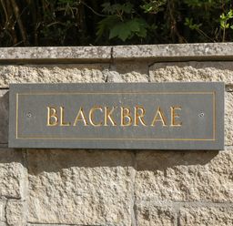 A stone wall with a plaque that reads Blackbrae at Blackbrae Cabin in Glenboig near Coatbridge Glasgow and Stirling