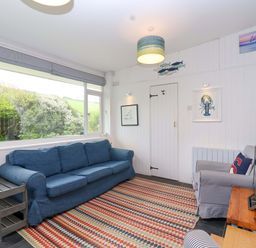 A living room with a sofa and television at 2 Brook Cottages in Hope Cove