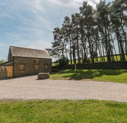 A house with a gravel driveway and trees at Penrhiwarwydd Barn Pontywaun