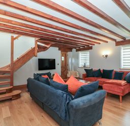 A living room with a staircase and sofa at Penrhiwarwydd Barn Pontywaun