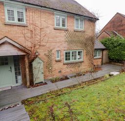 A brick house with green window frames and a door next to a wooden deck and garden at Hiraeth in Cwmtaf near Cefn-Coed-Y-Cymmer