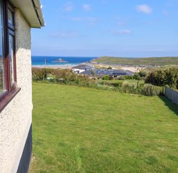 A view of the sea and houses from a garden at Pentreath in Crantock