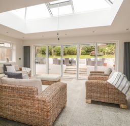 A living room with wicker furniture and sliding glass doors leading to a garden at The Orchard in Crantock