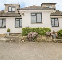 The exterior of a house with stone steps shrubs and plants at The Orchard in Crantock