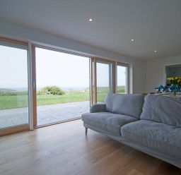 A living room with large sliding glass doors opening to a grassy outdoor area at Kareena in Crantock