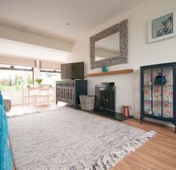 A living room with a blue cabinet and a dining area in the background at Keelyn in Crantock