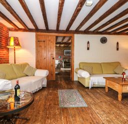 A living room with wooden beams on the ceiling two sofas and a coffee table at Downs View Dairy in West Tytherley
