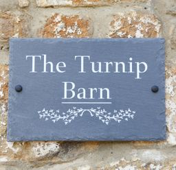 A sign displaying The Turnip Barn on a stone wall