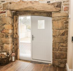 An entrance area with a stone wall and white door at The Turnip Barn in 