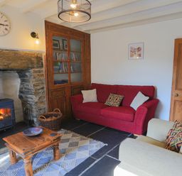 A living room with a red sofa a beige armchair a wooden coffee table and a fireplace at Moelwyn View Cottage in Llan Ffestiniog