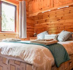 A bedroom with a bed and folded towels and pillows in Oak Lodge Constantine near Falmouth