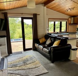 A living room with a sofa and kitchen area at Willow Lodge in Constantine near Falmouth