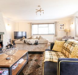 A living room with sofas a wooden coffee table a fireplace and a television at Coed Derw Isaf in Betws-Y-Coed