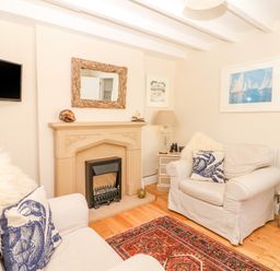 A living room with two armchairs fireplace mirror and wall-mounted tv at The Shell Seekers in Fowey