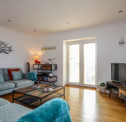 A living room with sofas a coffee table a TV and a shelf near glass doors at Tides Reach in Rhosneigr