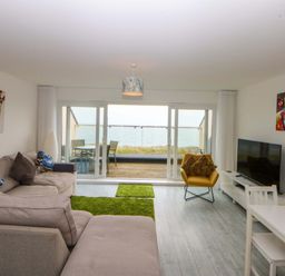 A living room with a sofa and television at Welymora in Pwllheli