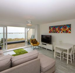 A living room with a sofa and dining area at Welymora in Pwllheli