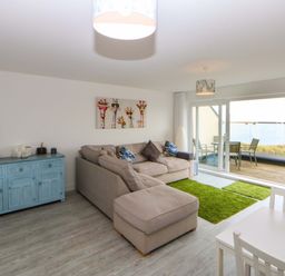 A living room with a sofa and dining table at Welymora Pwllheli