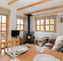 A small living room with a wood stove television dining table and leather sofa at Someplace Else in Diss