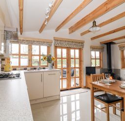 A kitchen and dining area with wooden beams on the ceiling and wood stove at Someplace Else in Diss