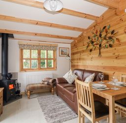 A small living and dining area with a wood stove sofa dining table and wall art at Someplace Else in Diss