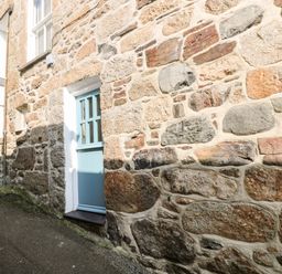 A stone exterior wall with a blue door and window at Mole Cottage in Mousehole