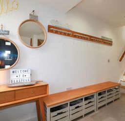 An entrance with mirrors, a lamp, a welcome sign, and a coat rack at Seaspell Beach House in Constantine Bay