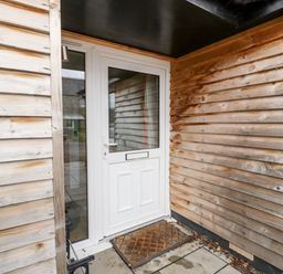 A white door with glass panels and a doormat outside at Vine Lodge in Kingsbury Episcopi near Martock