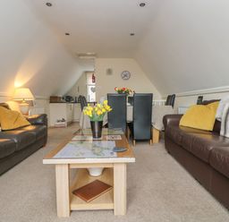 A living room with two sofas a coffee table with yellow flowers and a dining table with chairs at Valley Lodge 48 Callington