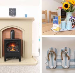 A fireplace with a black stove and a clock above it a wooden dining table with mugs and a vase of sunflowers and a wall hook shaped like flip flops at The Watch in Porthcurno