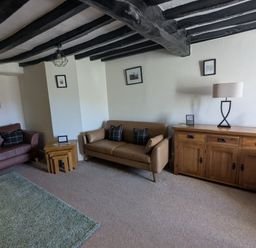 A living room with two sofas wooden side tables a wooden cabinet and a lamp at Gwrtheyrn in Dyffryn Ardudwy