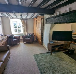 A living room with leather chairs a wooden cabinet a television and a green rug at Gwrtheyrn in Dyffryn Ardudwy