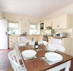 A kitchen with a wooden dining table set for six and cream cabinets at School House in Builth Wells