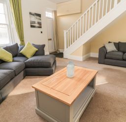 A living room with two grey sofas with cushions a wooden coffee table and a staircase at Hare amp Hounds House in Allendale