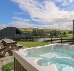 An outdoor area with a hot tub and picnic table at Glanyrafon St Harmon
