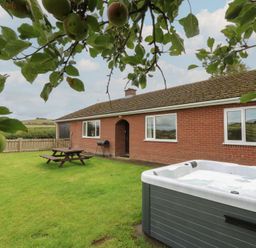 A garden with a house and hot tub at Glanyrafon Bungalow St Harmon