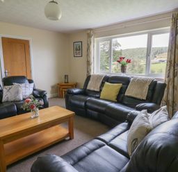 A living room with sofas and a coffee table at Glanyrafon Bungalow in St Harmon