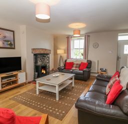 A living room with leather sofas a coffee table a television and a fireplace at Glasfryn in Llanfaethlu