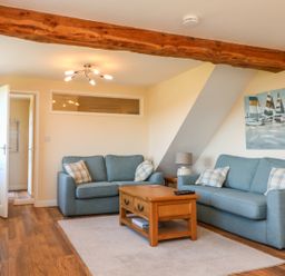 A living room with two blue sofas a wooden coffee table a television and wall art at Rose Cottage in Barnstaple