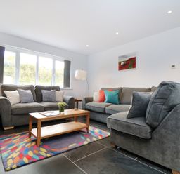 A living room with two gray sofas and a wooden coffee table on a colorful rug at Myles View in Pendeen