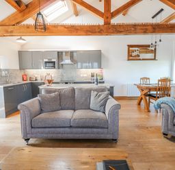 A living room with a sofa and kitchen area at Apple Tree Cottage Bleatarn near Kirkby Stephen