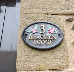A house number 3 plaque on a stone wall at Bracken Lodge in Wooler