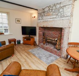 A living room with a stone fireplace a television two leather chairs and a round wooden table at Bracken Lodge in Wooler