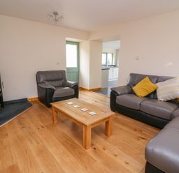 A living room with a wood-burning stove gray leather sofas wooden coffee table and yellow cushions at Bwthyn Eisteddfa Fach in Brynberian near Newport
