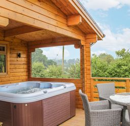 An outdoor space with a hot tub and seating area at Manor Farm Lodges - Red Kite Lodge in Newtown