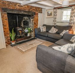 A living room with two gray sofas and a wood-burning stove in a brick fireplace at Janes Place in Lifton