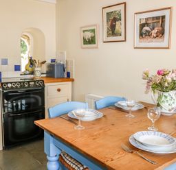 A kitchen with a wooden table set with plates and glasses and a stove with cream cabinets at Janes Place in Lifton