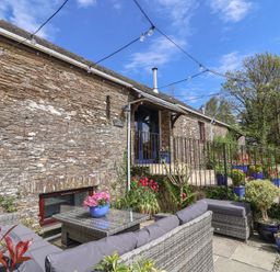 An outdoor seating area with a stone wall at Lily Cottage Looe