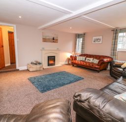 A living room with leather sofas a fireplace a television and carpet at Fisher Granary in Lampeter