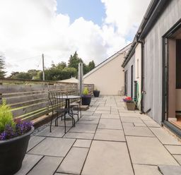 A paved outdoor terrace with metal table and chairs and flower pots at Underfell in Burton-In-Kendal